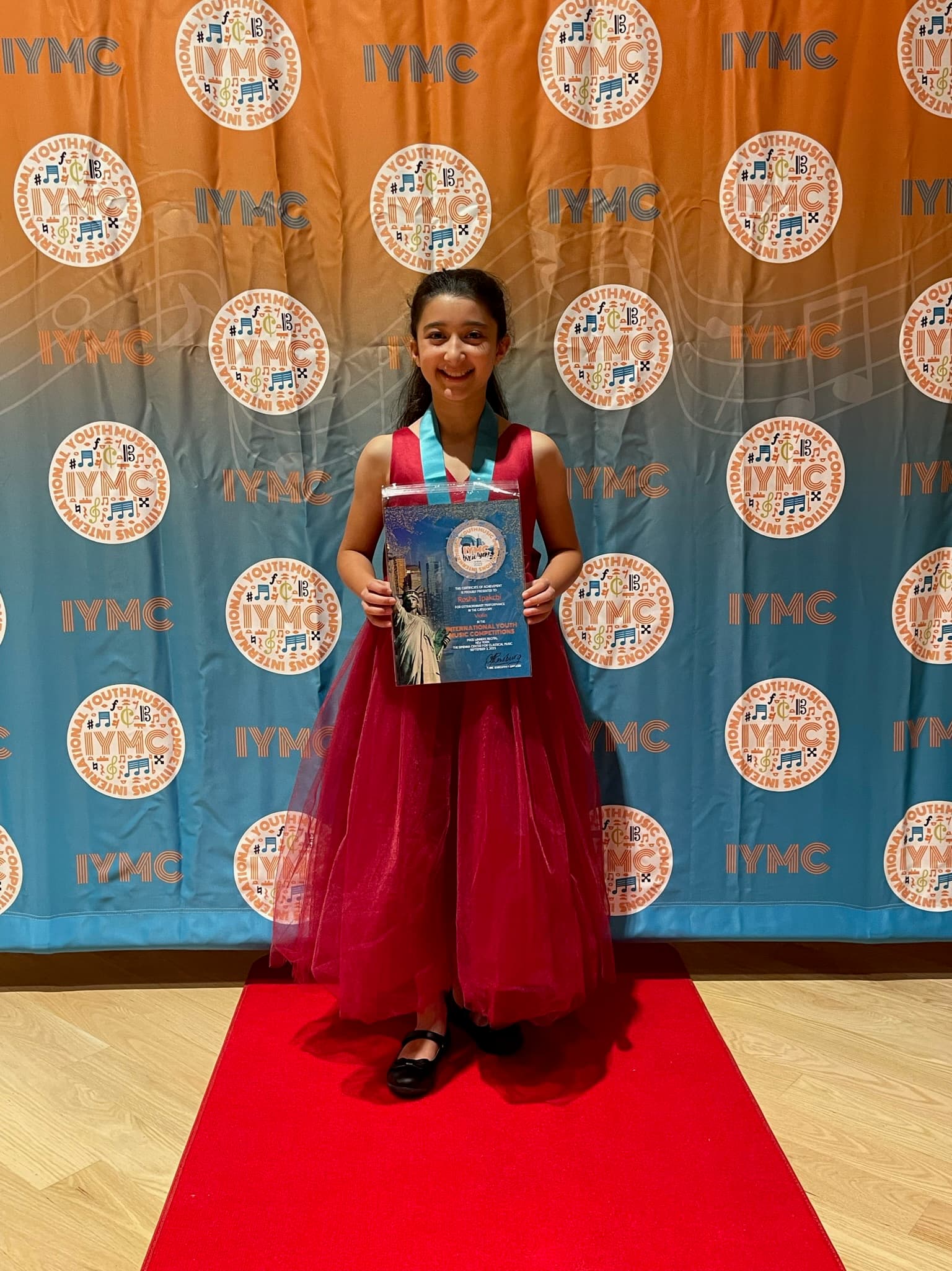 A young violinist beaming with her International Youth Music Competition certificate