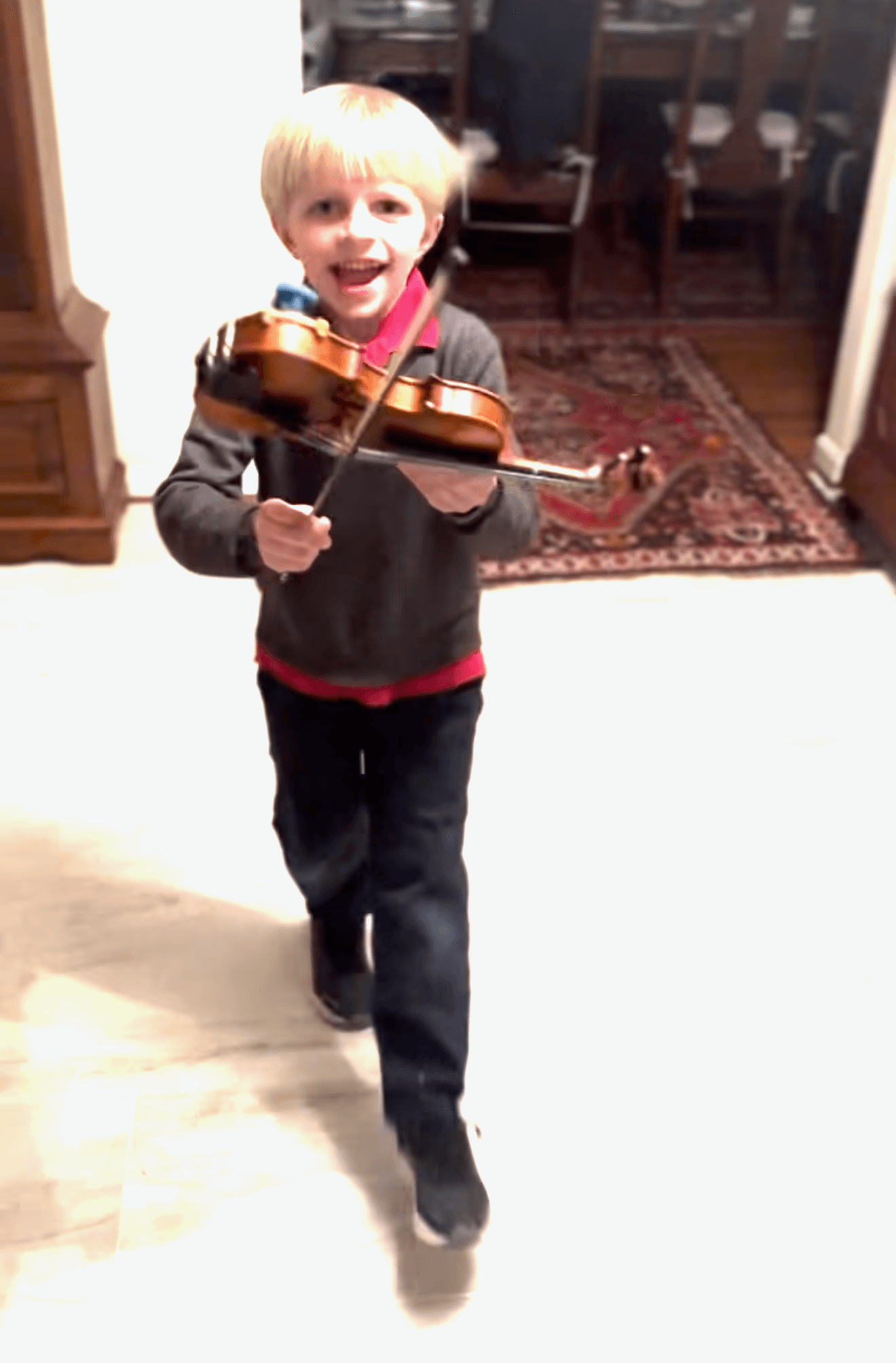 A boy drawing his bow across the strings at home